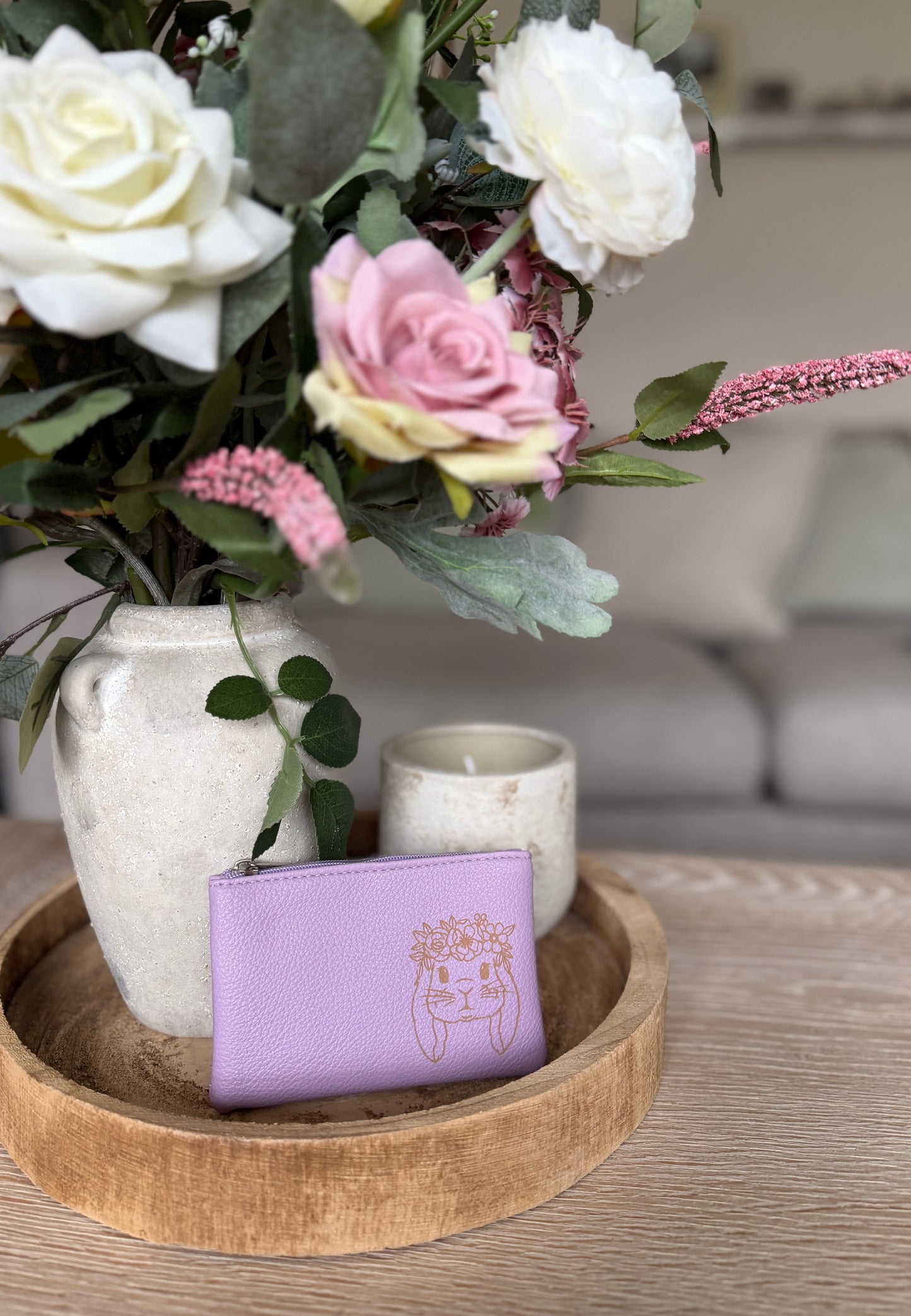 A purple coin purse with an image of a bunny with flowers and a candle in the background